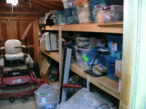 Storage shed interior with lawnmower and shelves of bins