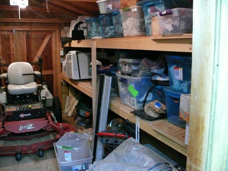 Storage shed interior with lawnmower and shelves of bins