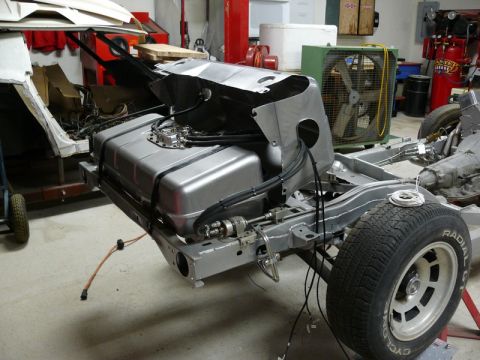 Silver fuel tank mounted on vehicle chassis with exposed wiring.