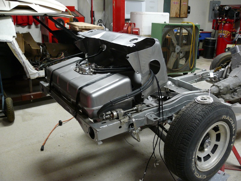 Silver fuel tank mounted on vehicle chassis with exposed wiring.