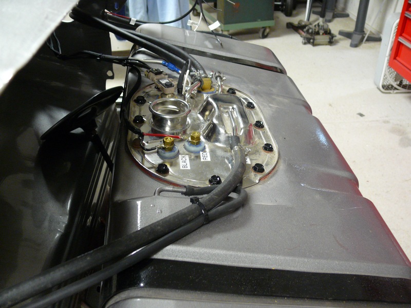 Gray fuel tank assembly with fuel pump module, hoses, and electrical connections.