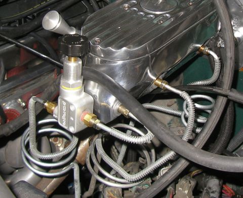 1990 Ford Bronco - Close-up of a polished aluminum brake fluid reservoir and proportioning valve assembly, with braided stainless steel lines connected to it.