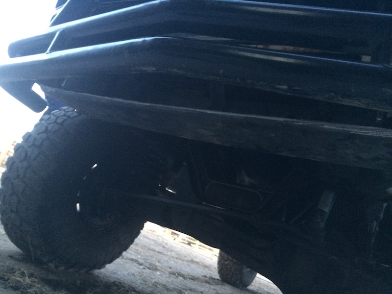 Close-up of a dark off-road vehicle's front bumper and tire.