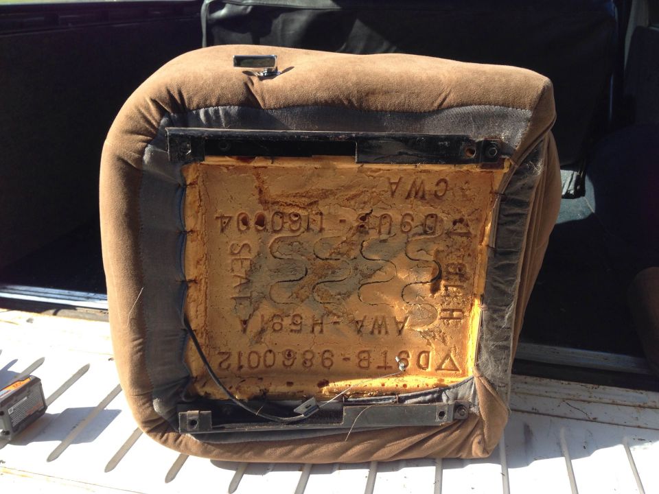 Underside of a car seat cushion with visible foam, springs, and stamped text.