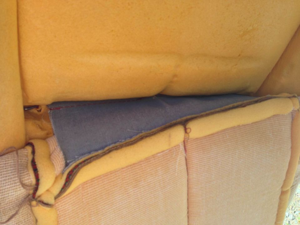 Close-up of yellow foam and grey fabric inside a vehicle seat.