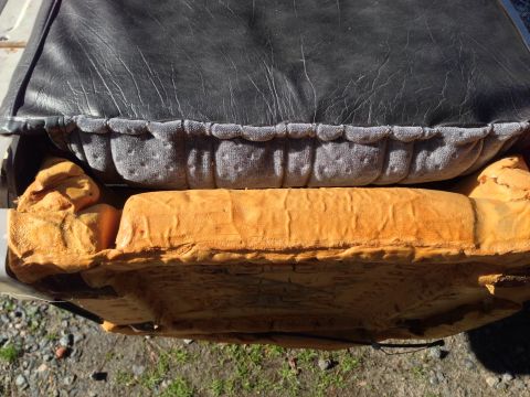 1979 Ford Bronco - Close-up view of a disassembled car seat, revealing the black vinyl top, gray fabric trim, and orange foam padding.