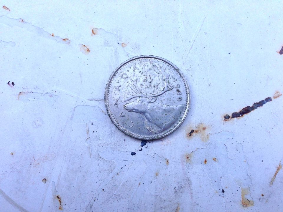 Canadian 25 cent coin on a white surface with rust stains