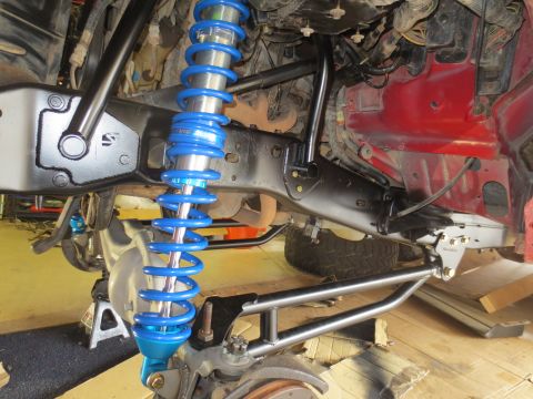 1996 Ford Bronco - The suspension system of a 1996 Ford Bronco is shown, featuring a bright blue coilover shock absorber and black suspension components. The…