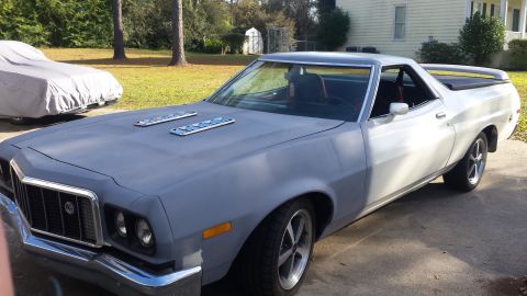 1976 Ford Ranchero - A light-colored Ford Ranchero is parked on a concrete driveway in front of a house. The front of the vehicle is painted gray primer and fea…