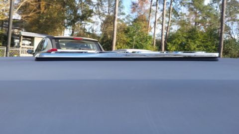 1976 Ford Ranchero - A close-up, low-angle shot shows the chrome trim detail on the edge of a vehicle's roof or bed cover. In the background, the rear of a silv…