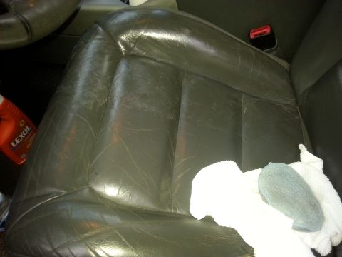 2001 Ford Explorer - A close-up view of a gray leather car seat with a bottle of Lexol cleaner and a white towel with a blue applicator pad resting on it.
