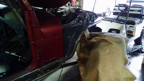 1985 Jeep CJ7 - A partially disassembled red Jeep CJ7 is shown in a garage setting, with a golf cart visible in the background. The Jeep's interior and eng…