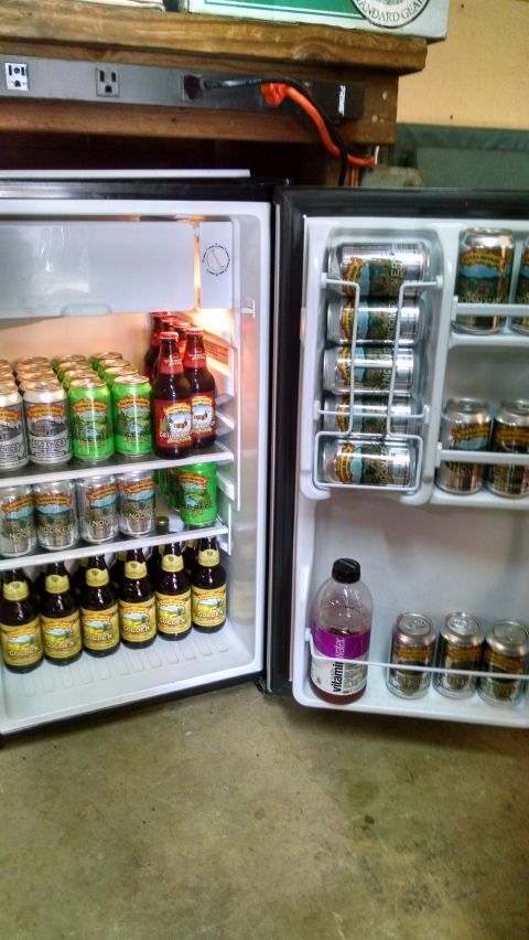 1985 Jeep CJ7 - A mini-fridge is stocked with various bottles and cans of beer, including Sierra Nevada brands. A bottle of Vitamin Water is also visible.