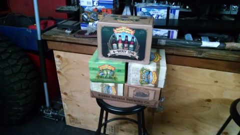 1985 Jeep CJ7 - A stack of Sierra Nevada beer boxes sits on a stool in front of a wooden workbench. The boxes include 4-Way IPA, Pale Ale, and Nooner.