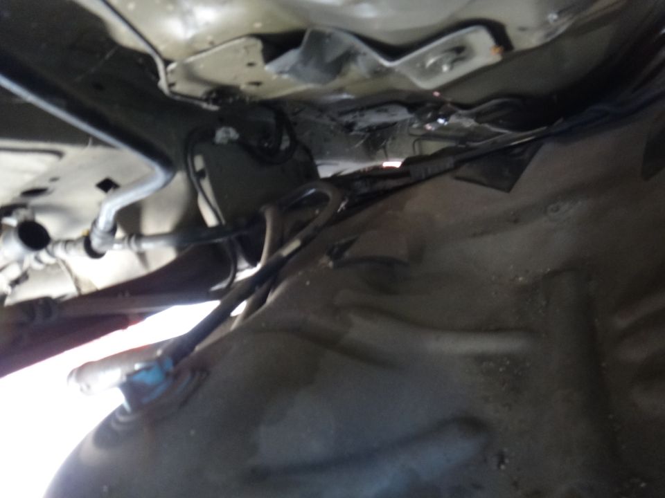 Underside of a vehicle showing fuel tank and lines.