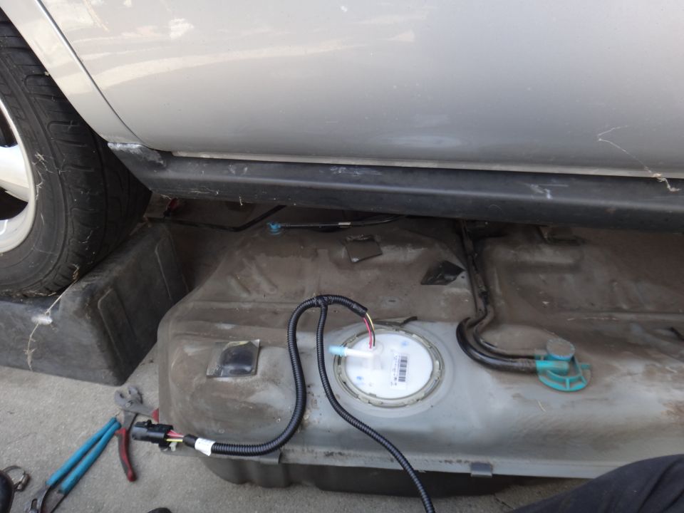 Silver sedan with fuel tank removed, showing wiring and fuel lines.