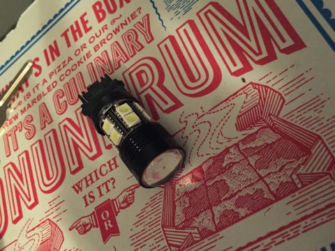 1991 Ford Bronco - A close-up of an LED bulb rests on a pizza box with red and white graphics. The box has text that reads "IT'S A CULINARY RUM" and "WHICH IS…
