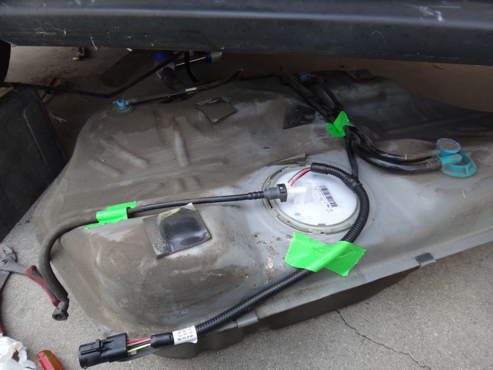 Fuel tank assembly with fuel lines and electrical connectors, secured with green tape.