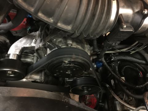 1996 Ford Bronco - A close-up view of the engine bay of a 1996 Ford Bronco, focusing on the serpentine belt system and supercharger components. The image show…