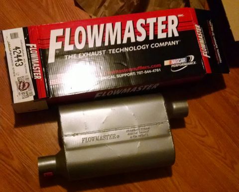 1994 Ford Bronco - A new Flowmaster muffler sits on a wooden floor next to its original packaging. The box is red and black with the Flowmaster logo and NASCA…
