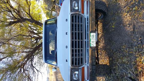 1978 Ford Bronco - The front view of a white Ford truck, possibly a Bronco, is shown with a chrome grille and a Colorado license plate reading "231 SOL". The…