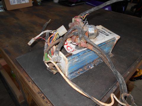 1992 Ford Bronco - A close-up view of an automotive wiring harness and a control box resting on a workbench.
