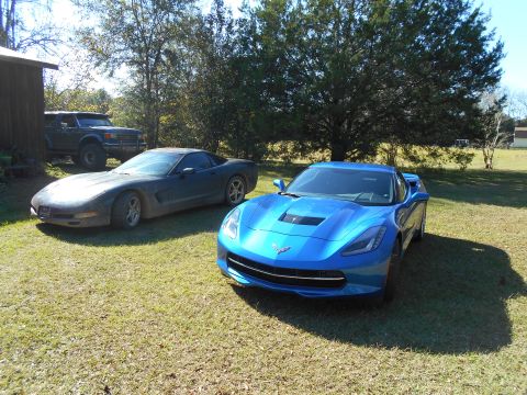 1992 Ford Bronco - Two Chevrolet Corvettes and a Ford Bronco are parked on a grassy area next to a building.