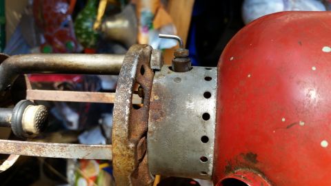 1992 Ford Bronco - Close-up of a rusty metal bracket attached to the red body of an old lantern.