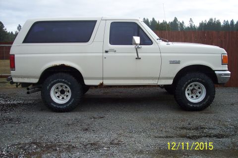 1990 Ford Bronco - Side view of a white 1990 Ford Bronco with aftermarket wheels and some rust.