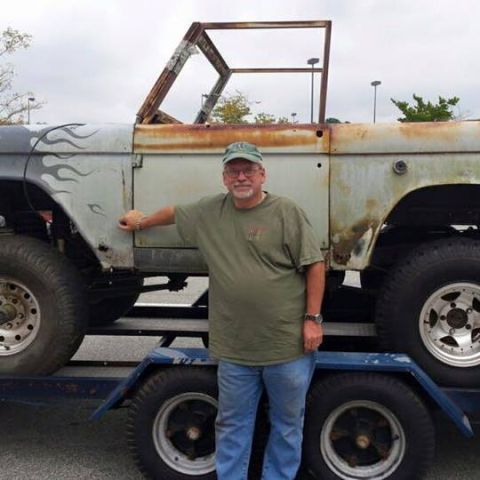 1972 Ford Bronco - A man stands beside a weathered 1972 Ford Bronco, which is loaded onto a trailer for transport.