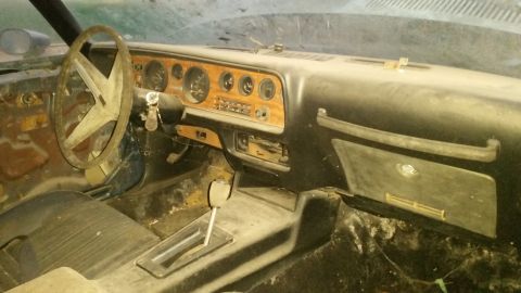 1970 Pontiac Firebird - The dusty interior of a 1970 Pontiac Firebird shows its dashboard, steering wheel, and automatic transmission shifter.