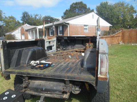 1972 Ford Bronco - The rear of a pickup truck is shown in a state of disassembly, with tools laid out on the bed.