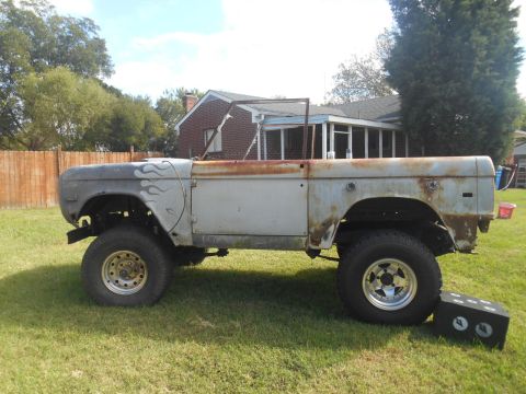 1972 Ford Bronco - Side view of a weathered Ford Bronco body with flame decals, showing signs of restoration.