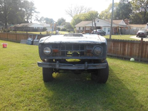 1972 Ford Bronco - This 1972 Ford Bronco, seen from the front, appears to be undergoing restoration with its weathered exterior and hood scoop.