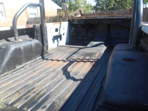 1972 Ford Bronco - The interior of a vehicle shows a worn metal bed and exposed parts, suggesting a restoration project.