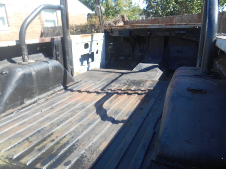 Corrugated metal bed of a weathered vehicle interior with a roll bar and exposed components