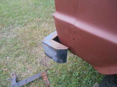 1972 Ford Bronco - Close-up of a vehicle's rear corner, showing a bumper and some parts on the grass.