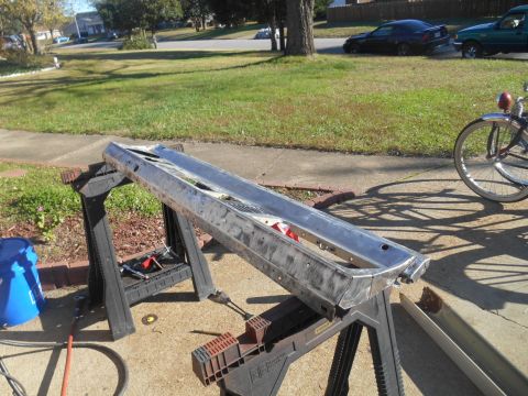 1972 Ford Bronco - Car bumper undergoing restoration outdoors, with a bicycle and other vehicles visible in the background.