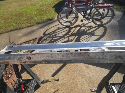 1972 Ford Bronco - A vehicle part, possibly a bumper or frame section, is laid out for work with a bicycle in the background.