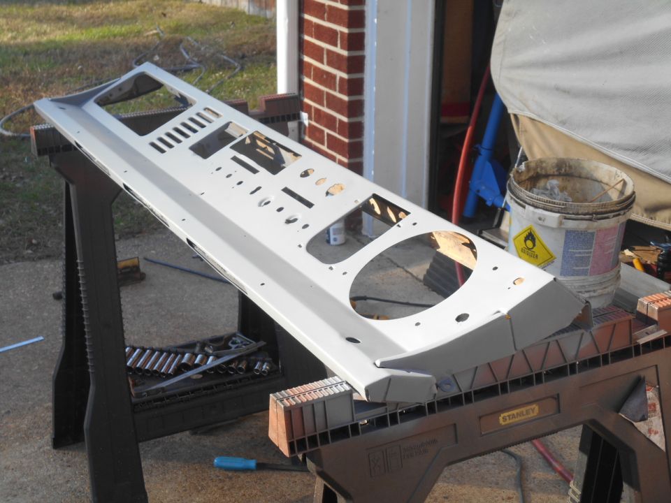 Gray dashboard panel with numerous cutouts for gauges and controls, resting on sawhorses