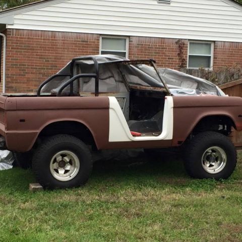 1972 Ford Bronco - A brown Ford Bronco is undergoing restoration, viewed from the side with its doors and top removed.