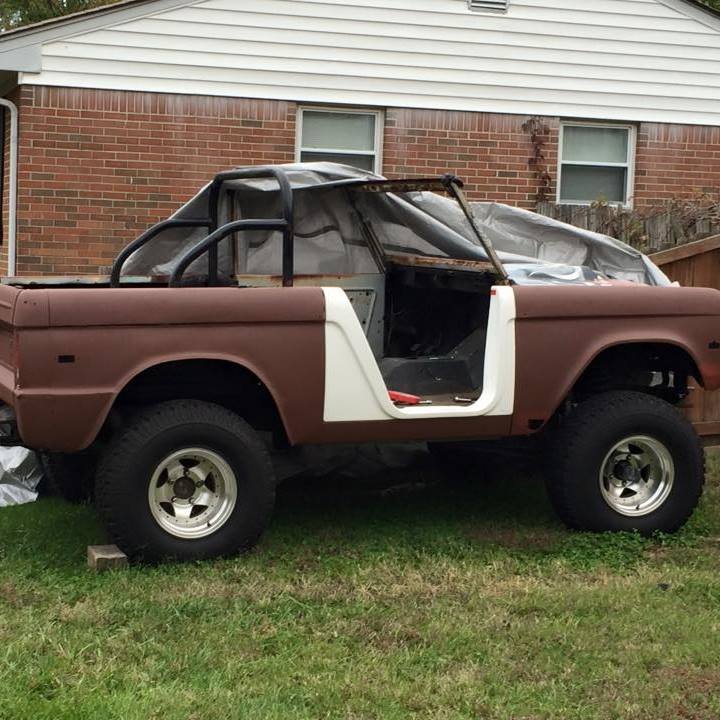 Brown Ford Bronco in restoration with roll cage, missing doors and top