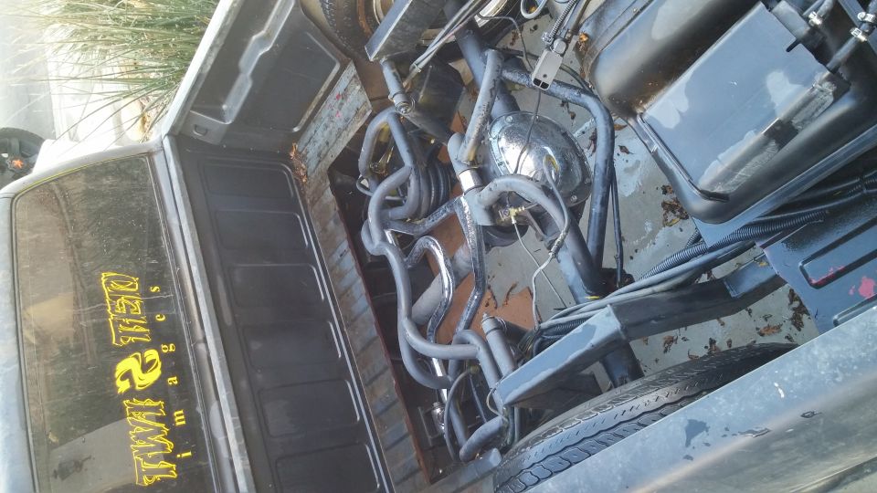 Truck bed with a complex, shiny exhaust system and a fuel tank. Yellow text on the window reads 'TWIN 2 IMAGES'