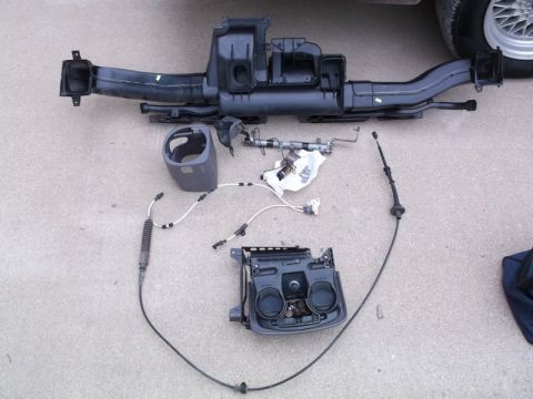 1999 Mercury Grand Marquis - Disassembled car parts, possibly for a console installation, are spread out on a paved surface.