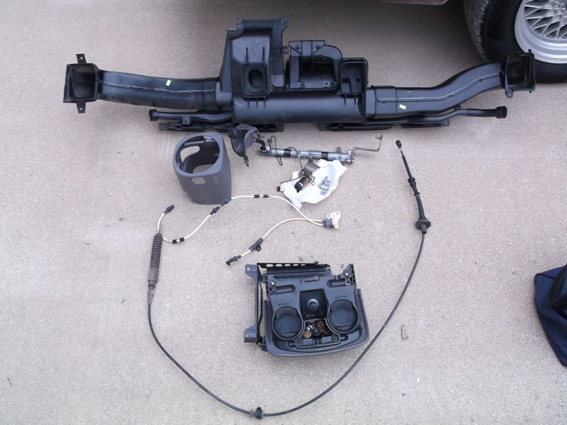 Car interior parts laid out on the ground, including ducting and a center console piece