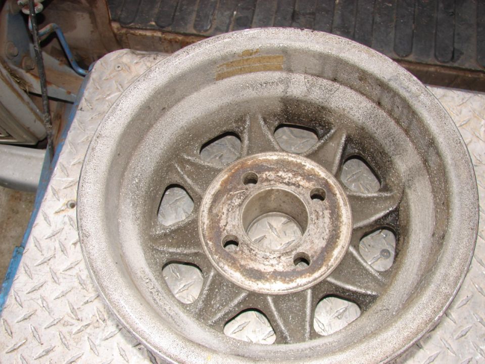 Close-up of a dusty, silver alloy car wheel with a star-like spoke pattern