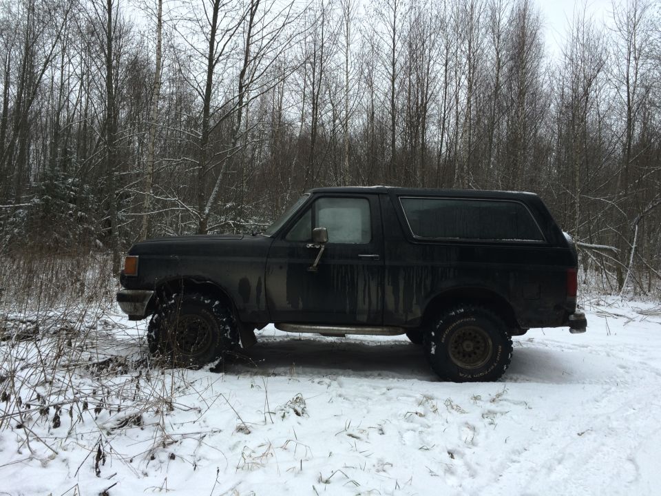 Side view of a black 1987 Ford Bronco in the snow