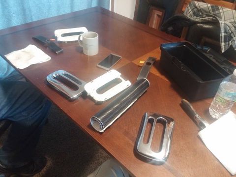 2000 Mercury Grand Marquis - Interior trim pieces, including chrome bezels and a carbon fiber wrap, are laid out on a wooden table.