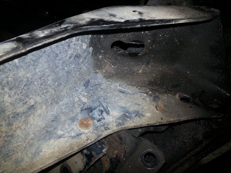 Close-up of vehicle frame with rust spots and holes