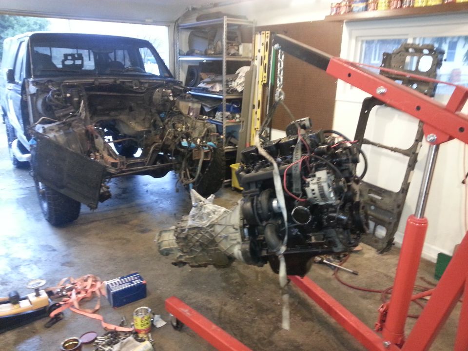 Disassembled black Ford Bronco in garage with engine removed
